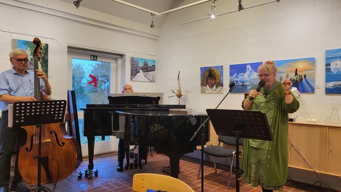 Musikere, der optræder med en pianist, cellist og sanger i et galleri-lignende miljø med kunstværker på væggene.