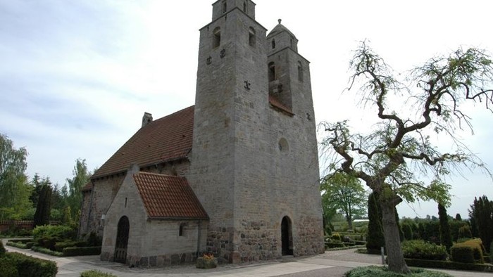 En middelalderlig kirke med to tårne og røde tag.
