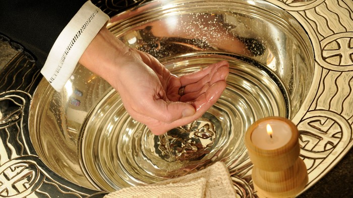 Hånd ryster salt i stor sølvbåde med lysende lys og duk