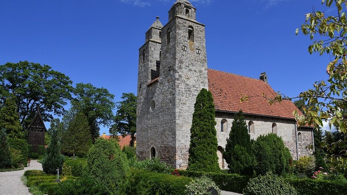 Et middelalderligt kloster med tårn og røde tag i en træket garden