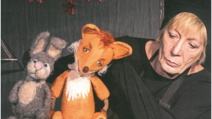 Plakat für ein Kindertheaterstück mit einer Frau und Puppen.