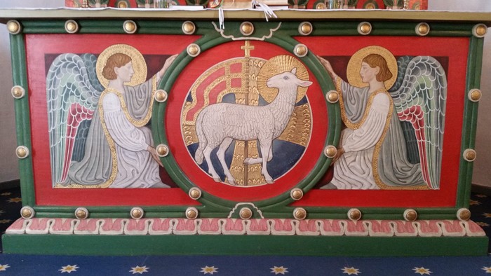 Billedet viser en prægtig altertavle med malerier af engle og en lamgud