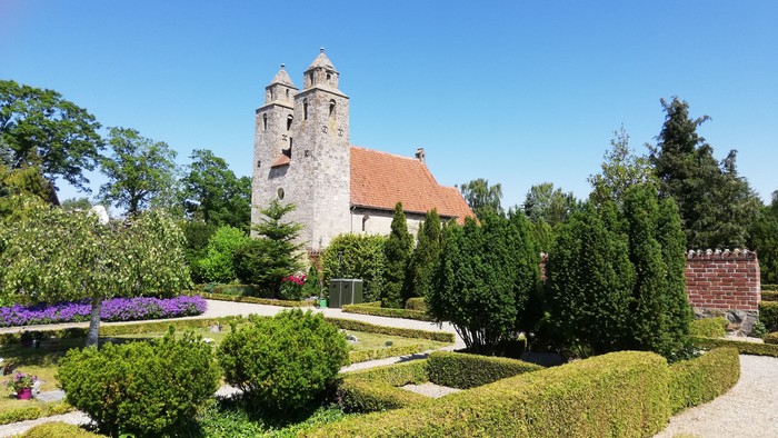 Et slot med tårn og grønne haver under en klar blå himmel