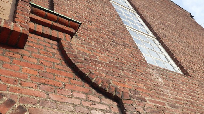 Røde mursten med smal vinduesåbning og rør.