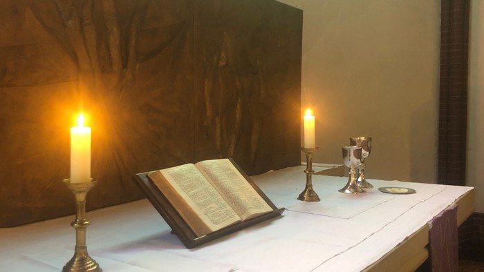 Altar der Auenkirche mit Bibel, brennenden Kerzen, Abendmahlskelch und Patene