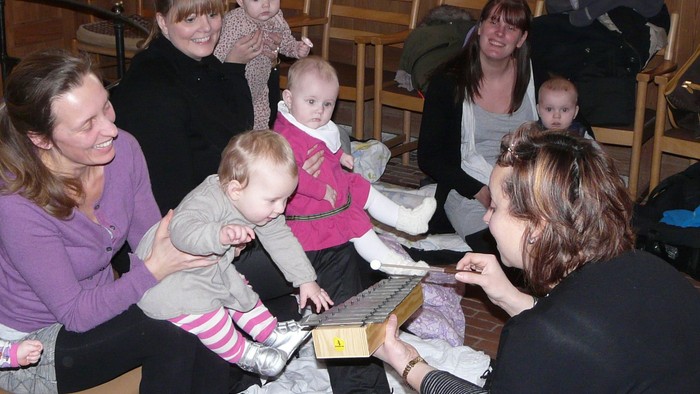 En gruppe af kvinder og børn sidder om en bord og spiser.