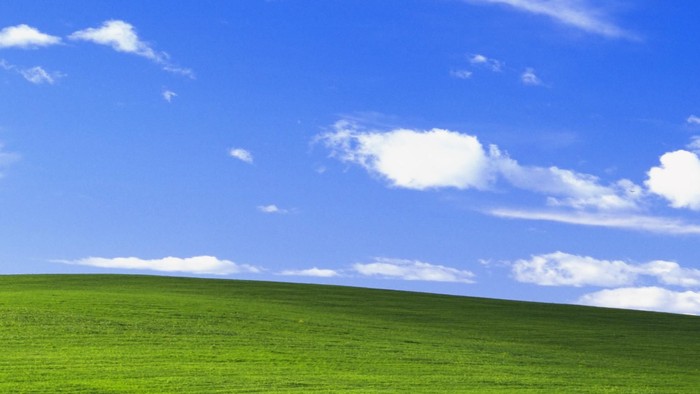Rolling green hills under blue sky with white clouds