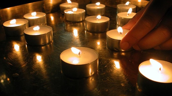 En hånd tænder lyse lygter på en metallplade