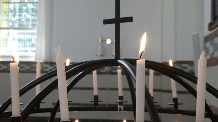 En kandleholder med lysende lygter og et kors i kirkeindretning