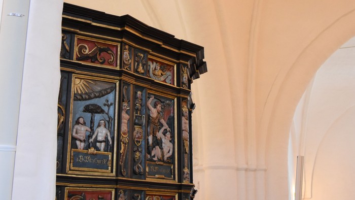 Historisk prædikestol inde i en prægtigt udsmykket kirke med indviklede udskæringer og religiøs kunst.
