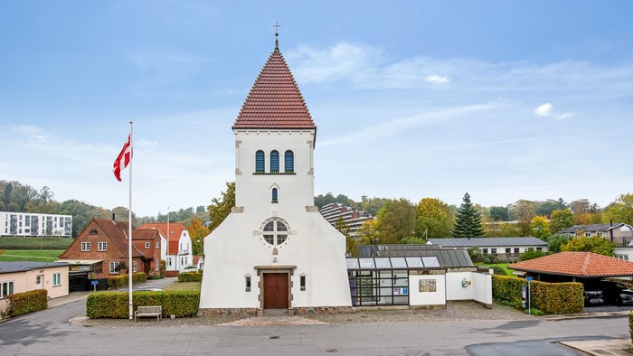 En lille kirke med tårn og en canadisk flag i forgrunden