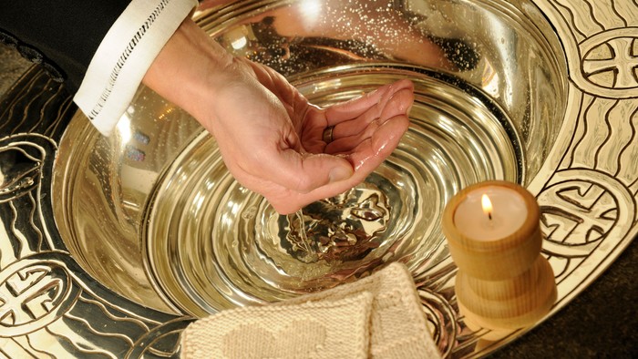 Hånd ryster salt i stor sølvbåde med lysende lys og duk