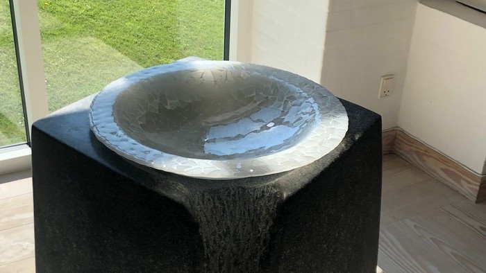 En moderne fontæne i et indendørs område med glaspanelet bagud