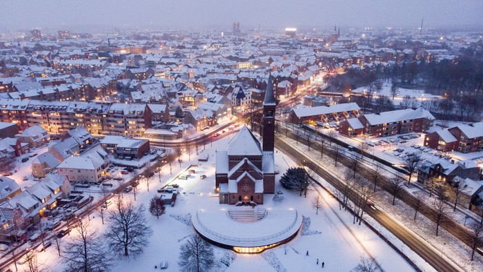 Byen dækket af sne med lysende bygninger og kirke i midten