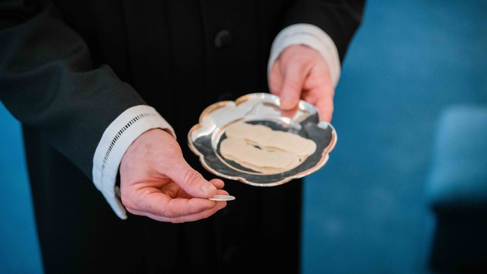 En person i mørkt tøj holder en smørrebrødsked og en small med mad.