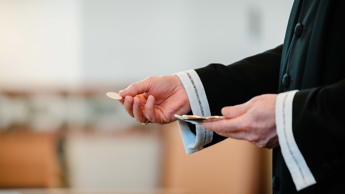 En person i mørkt tøj holder en lille papirflæske og en pen.