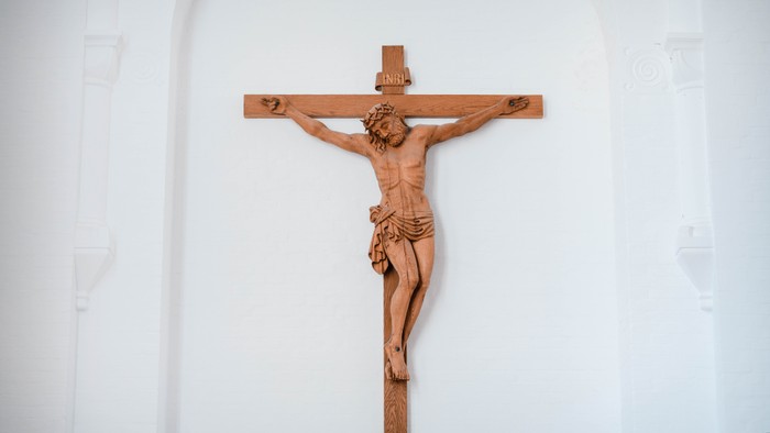 En træskulptur af Jesus Kristus på korset på en hvid væg
