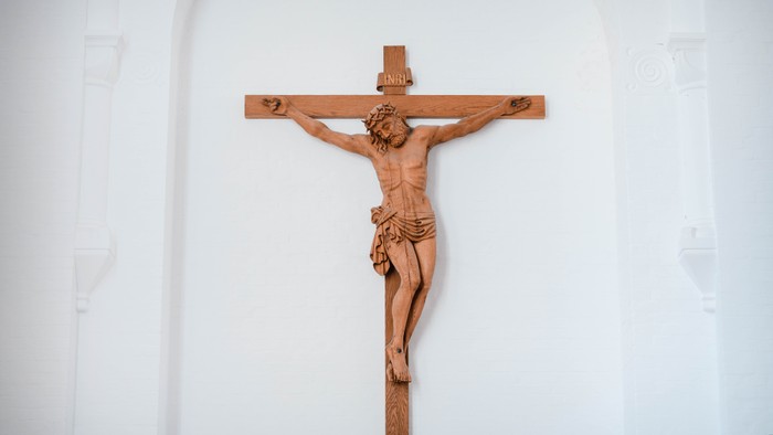 En træskulptur af Jesus Kristus på korset på en hvid væg