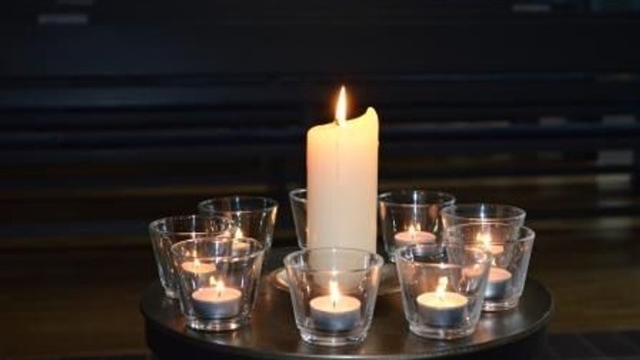 Elegante Kerzenanordnung mit einer hohen Mittelkerze, umgeben von kleineren brennenden Kerzen in Glasbehältern.