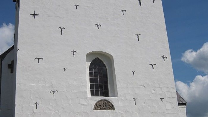 Hvide kirke med kryds på vægge og vindue.