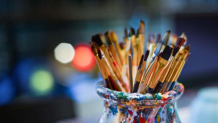 En farverig vase med malerbrushes på et bord