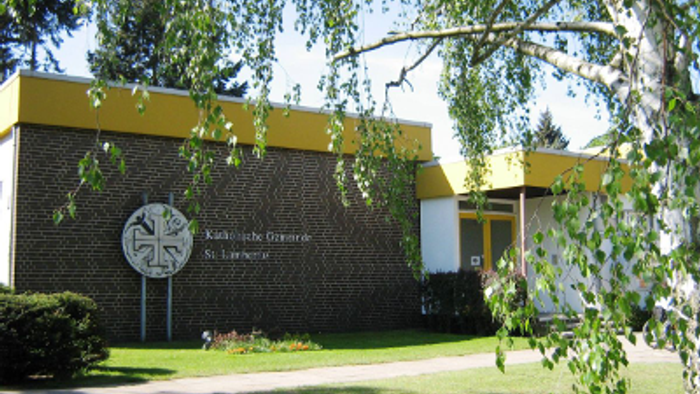 Das Bild zeigt ein Gebäude der Katholischen Universität St. Georgen mit einem gelben Dach und einem Baum davor.
