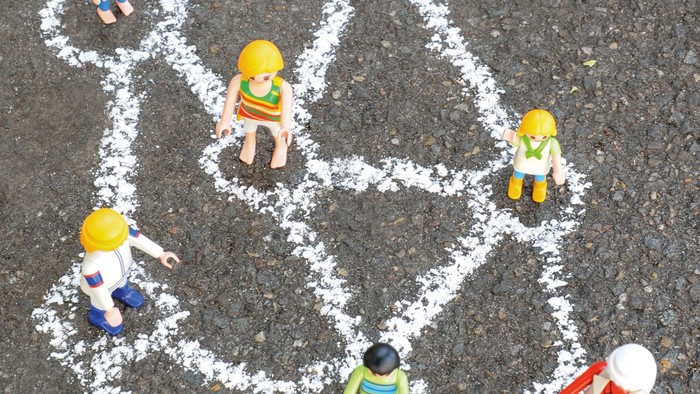 Mit Kreide gezeichnete Bauarbeiterfamilie mit Spielzeugfiguren auf einem Gehweg.