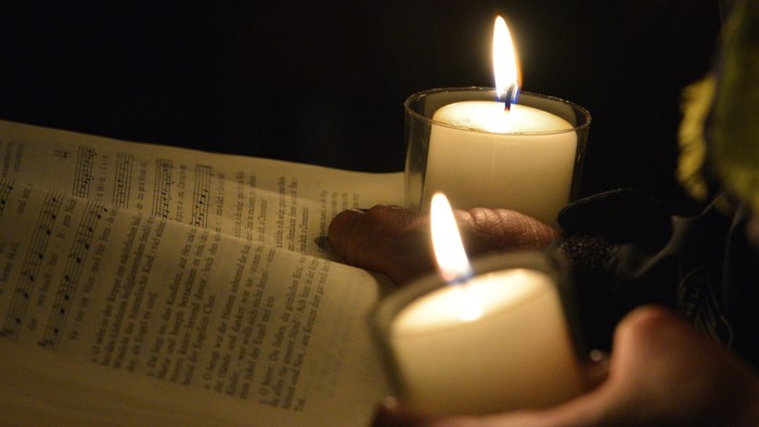 Drei brennende Kerzen auf einem Buch im Dunkeln