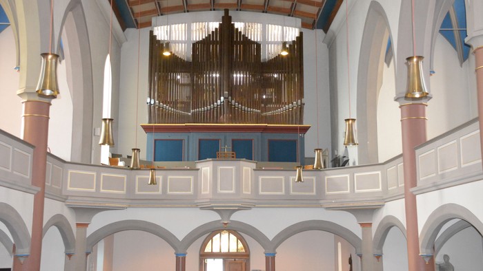 Große Kirchenorgel in einem weißen Kircheninneren mit Rundbögen und Säulen.