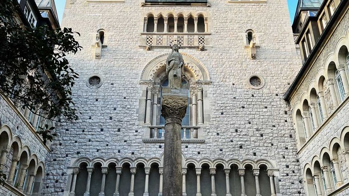 Gothischer Turm mit Uhr und Statue im Vordergrund
