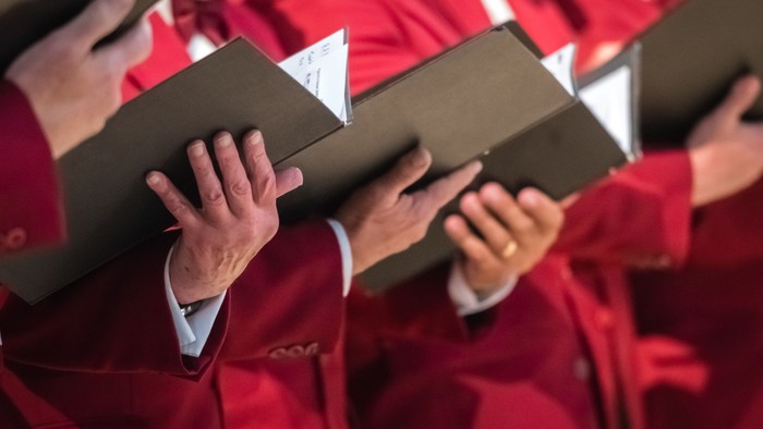 People in red robes holding black boxes.