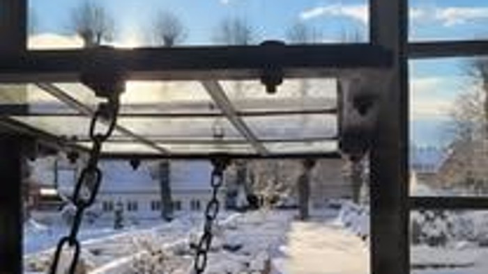 En snødekt have med en seng og kælderåbning.