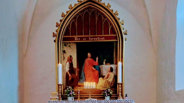 Alter i kirke med lysede lysstaker foran