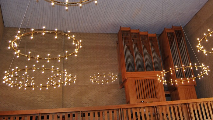 En stor kirkeindgang med hængende lyskæder og orgel.