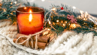 Weihnachtliche Deko mit brennender Kerze, Tannenzweigen und Lichtern