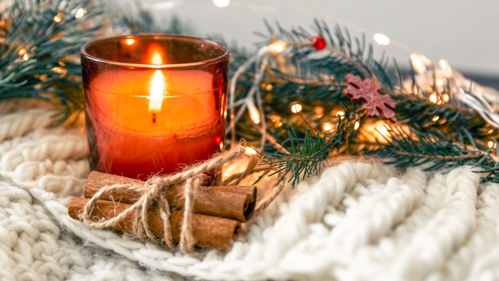 Weihnachtliche Deko mit brennender Kerze, Tannenzweigen und Lichtern