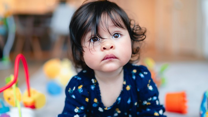 Ein kleines Kind sitzt auf dem Boden und schaut zur Seite.