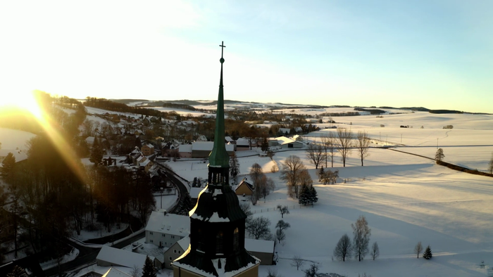 Schneebedeckte Landschaft mit Kirche und Sonnenuntergang
