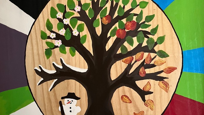 Bunter Kreis mit Baum und Schneemann, beschriftet mit 