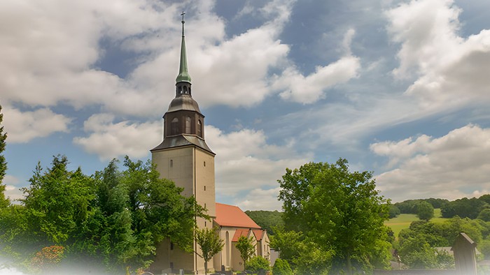 Kirchturm mit spitzem Dach in ländlicher Umgebung