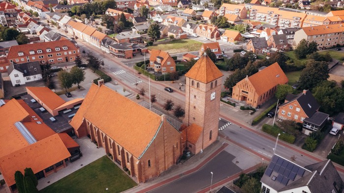 Overblik over landsby med kirke og røde tag.