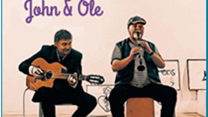 To mænd, der spiller guitar, den ene synger ind i en mikrofon, med teksten *