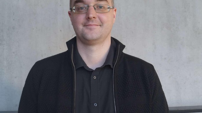 Mand med briller og sort jakke.