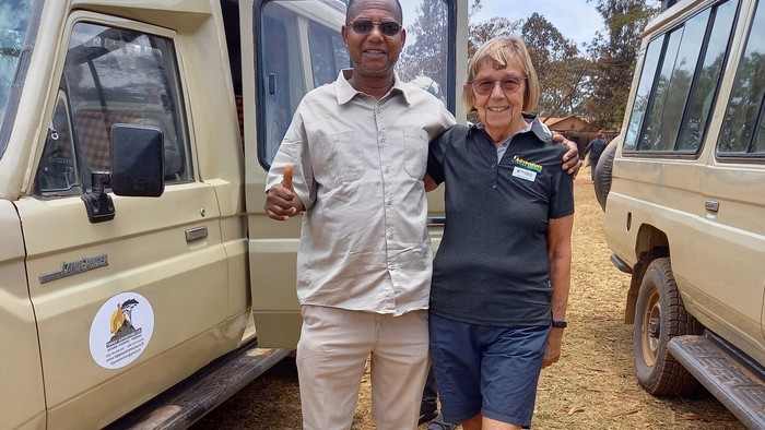 To personer, der står mellem to køretøjer udendørs.