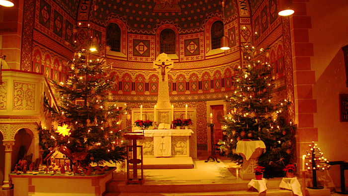 In der Kirche stehen zwei Weihnachtsbäume vor dem Altar.