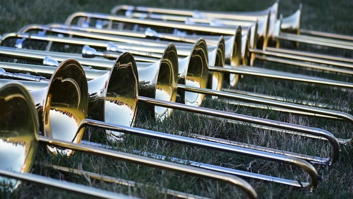 Eine Reihe polierter Tuben aus Messing, die im Freien auf einem grasbewachsenen Feld aufgestellt sind.