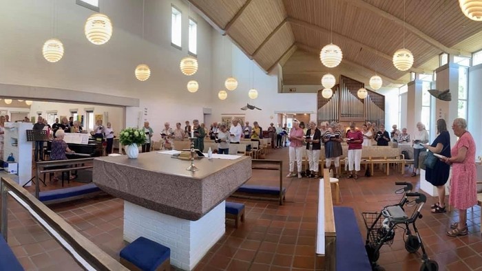 En stor hall med mange mennesker, der deltager i aktiviteter og snakker.