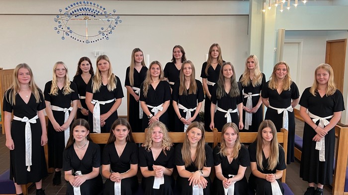 En gruppe kvinder i svart og hvidt tøj samlet i kirke.