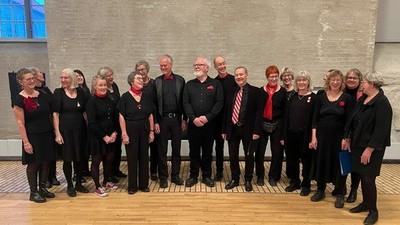 Gruppe af mennesker i formelt tøj, der poserer sammen indendørs, sandsynligvis til et kor- eller begivenhedsbillede.
