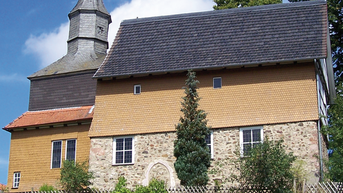 Das Bild zeigt ein altes, gelbes Gebäude mit einem Turm und einem steilen Dach.